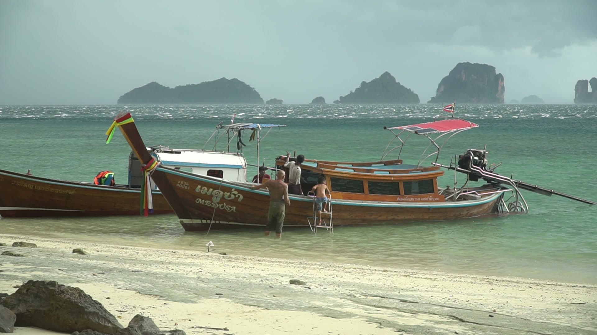 Private longtail boat on a beach with limestone islands behind